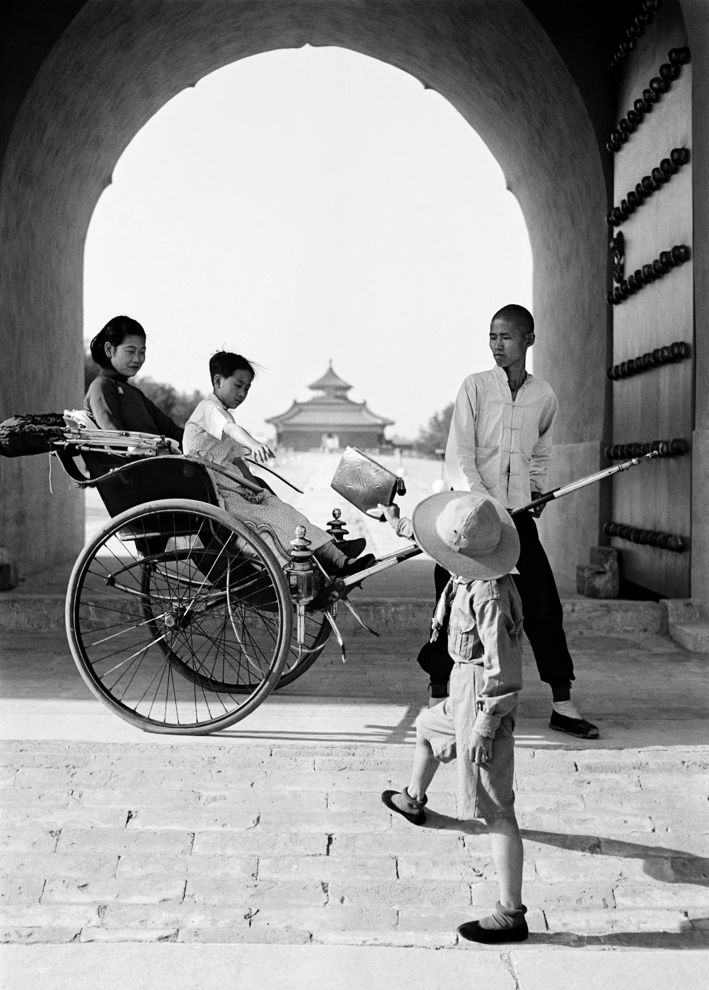 將皮包遞給坐在人力車上的母子。
     瓦特爾‧博薩特
     中國，約1937年。