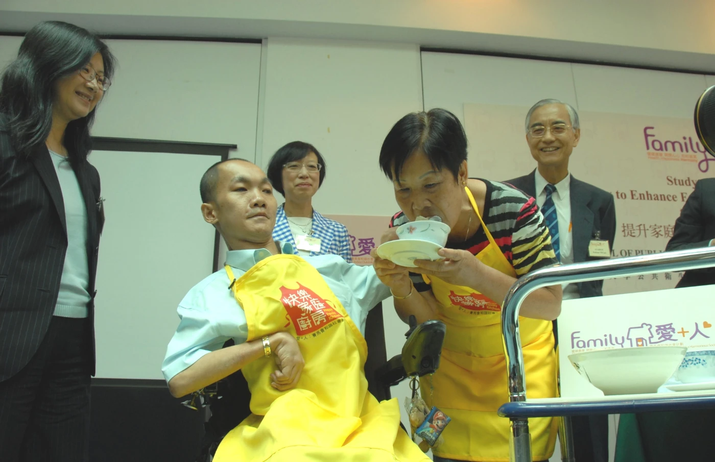 Mr. TANG Chi-ying (in yellow apron), participant of the “Happy Family Kitchen” Project, feeds his mother with his hand-made dumplings to show his care